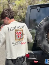 Remera marrón con estampado de un reloj dorado y la frase "Who wears a watch in Ibiza?".