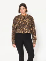 Buzo estilo bomber con estampado animal print, acceso con botones snap, largo hasta la primera cadera y logo bordado en una manga.