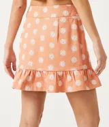 Conjunto de pollera corta y top color salmón con estampado de flores blancas. El top es corto con tirantes finos y la pollera tiene volados en el ruedo.