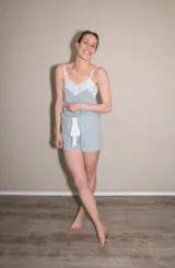 Pijama de short y musculosa color celeste con textura acanalada. La musculosa tiene escote en V con detalle de puntilla blanca y tirantes finos blancos. El short tiene elástico y lazo blanco en la cintura.