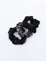 Pack de tres coleros para el pelo, uno de terciopelo negro, uno de satén negro y uno estampado con flores y calaveras en blanco y verde sobre fondo negro.