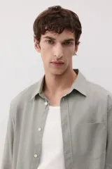 Camisa manga larga color verde oliva, de corte recto, con cuello inglés, tapeta clásica, canesú en la espalda, bolsillo superior abierto, cierre ajustable de botón en los puños y bajo redondeado.