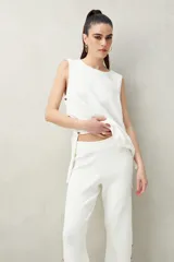 Pantalón negro de punto con calce relajado, caída fluida y botones dorados en los laterales.