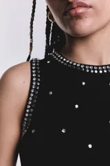 Musculosa negra con cuello redondo y detalle de strass y tachas plateadas en el frente y los bordes.