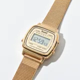 Reloj digital dorado con malla metálica.