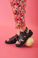 Sandalias negras con plataforma, tiras anchas cruzadas con textura simil cuero de cocodrilo y hebilla lateral.