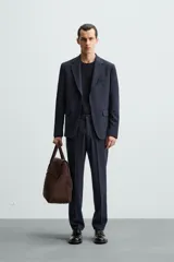 Pantalón de vestir azul marino, de corte slim fit, confeccionado en tejido con 17% de lana. Cuenta con bolsillos frontales y traseros de doble vivo con botón. Cierre frontal con cremallera y botón.