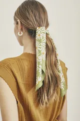 Pañuelo de poliéster color verde con estampado de margaritas blancas y borde naranja.