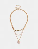 Collar corto dorado de tres capas: una con mostacillas doradas, otra con dijes de corazones y otra con dije circular rosa.