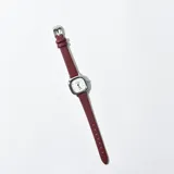 Reloj de pulsera con caja plateada de forma cuadrada y correa de cuero sintético color borgoña.