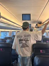 Remera celeste con estampa de paisaje costero y texto "Ittai Stars" y nombres de ciudades.