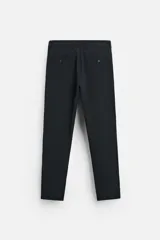 Pantalón slim fit negro confeccionado en tejido con elasticidad en ambas direcciones. Cuenta con bolsillos frontales y traseros de vivo con botón. Cierre frontal con cremallera y botón.