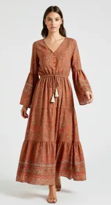 Vestido largo color naranja con estampado paisley, escote en V, mangas largas acampanadas y cintura elastizada con lazo ajustable.