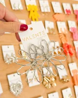 Aretes colgantes grandes de metal plateado, con diseño de dos flores estilizadas superpuestas y textura rugosa.