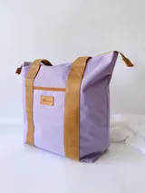 Bolso tipo tote de lona color fucsia con asas de cuero marrón, bolsillo interno y externo.