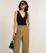 Pantalón wide leg color beige, de corte sastrero, con pliegues delanteros y cinturón.