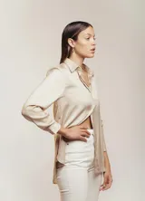 Camisa color beige claro de satén con cuello clásico, mangas largas con puños abotonados y cierre frontal con botones.