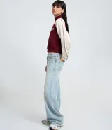 Saco femenino de poliviscosa, color blanco con mangas raglán marrones y ribetes blancos. Tiene cuello alto, cierre frontal de cremallera y bordado lettering "Kansas City" en el pecho.