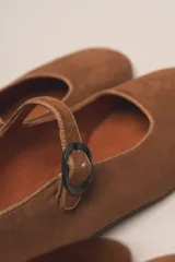 Zapato estilo Mary Jane color marrón, de cuero, con punta redondeada y tira sobre el empeine con hebilla.