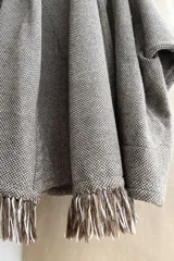 Saco de lana color marrón claro, con mangas amplias, cuello tipo bufanda con flecos y bolsillos laterales. Diseño oversize sin forro.