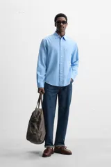 Camisa celeste de lyocell y algodón, corte relaxed fit, cuello solapa, manga larga con puños abotonados, bolsillo de parche en el pecho y cierre frontal con botones.