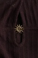 Vestido largo marrón de punto pointelle con estilo crochet, corte entallado, escote halter en V, adorno de metal en forma de sol en el centro del busto y falda sirena con bajo recto.