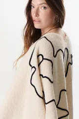 Ruana color marrón con flecos y bordados en el contorno.