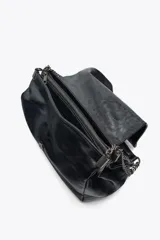 Bolso de hombro marrón oscuro de cuero sintético, con solapa y cierre magnético. Tiene un asa de cadena plateada y tres compartimentos internos, uno de ellos con cierre de cremallera.