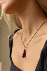 Collar dorado con cadena fina y dije colgante en forma de lágrima de piedra natural azul con vetas blancas.