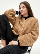 Campera negra de tela tipo sherpa con cierre frontal y cuello redondo.
