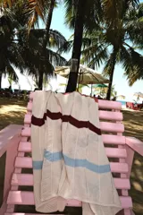 Camisa de tejido de punto oversize con botones en el frente y diseño a rayas horizontales en tonos beige, rojo, marrón y celeste.