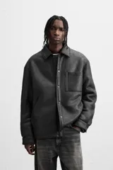 Sobrecamisa marrón de efecto piel con interior de borreguillo combinado a tono, de corte relaxed fit, cuello solapa, manga larga con puños abotonados, bolsillos de plastrón en pecho y laterales en cadera, efecto lavado y cierre frontal con botones a presión.