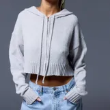 Cárdigan corto gris de punto con capucha, cierre frontal con cremallera y mangas largas.