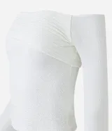 Blusa blanca texturizada con escote asimétrico hombro a hombro y mangas largas.