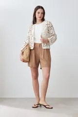 Chaqueta corta color crudo, tejida a crochet con diseño calado.