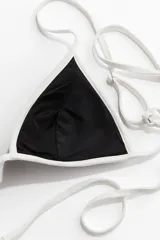 Top de bikini negro con forma triangular y ribete blanco.