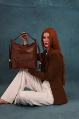 Cartera mochila color tostado, símil cuero, con compartimiento principal amplio y bolsillos frontales con cierre. Tiene correas ajustables para usar como mochila y asa superior para llevar al hombro.