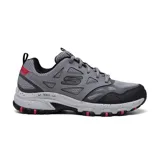 Championes Skechers Hillcrest Vast Adventure, color gris con detalles en negro y rojo. Capellada de cuero sintético y malla, entresuela moteada con absorción de impactos, plantilla Memory Foam y suela de goma flexible.
