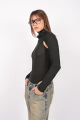 Body gris de tejido de punto con cuello alto y mangas largas. Presenta aberturas en los hombros y broches en la entrepierna.