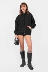 Buzo hoodie negro oversize con bolsillo canguro, cordones ajustables y roturas en terminaciones.