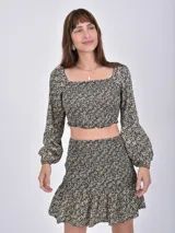 Minifalda negra con estampado floral en tonos beige, con cintura elastizada y volados en el ruedo.