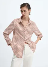 Camisa de manga larga con cuello camisero y cierre de botones frontal. Estampado geométrico en tonos terracota y blanco.