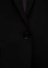 Blazer negro de corte entallado, con solapas de muesca, cierre de un botón, dos bolsillos de solapa y puños abotonados.