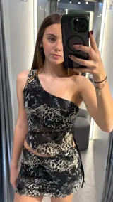 Conjunto de top asimétrico de un solo hombro y minifalda con estampado animal print en tonos grises y negros.