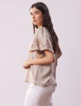 Blusa color beige de crepe, marca Batía, con cuello a la base y escote en V. Manga corta amplia con bordados.
