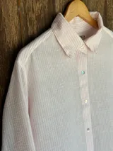 Camisa a rayas verticales, con cuello clásico y cierre frontal con botones.