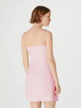 Vestido corto color amarillo pálido, con breteles finos, escote en V cruzado y lazo en la cintura.