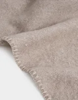 Bufanda triangular color beige con flecos trenzados.