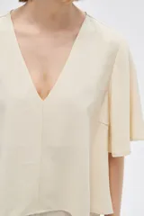 Blusa color crema de viscosa con escote en V y mangas cortas acampanadas.