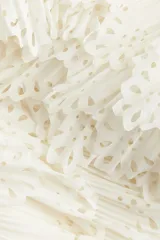 Minifalda color crudo de crepé de gasa con volados plisados y diseño calado. Tiene cierre oculto y cierre de corchete a un lado. Está forrada.